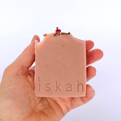 Hand holding a bar of soap with 'iskah' branding against a white background
