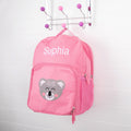 Pink personalised kids backpack with embroidered child's name and smiling koala face print.