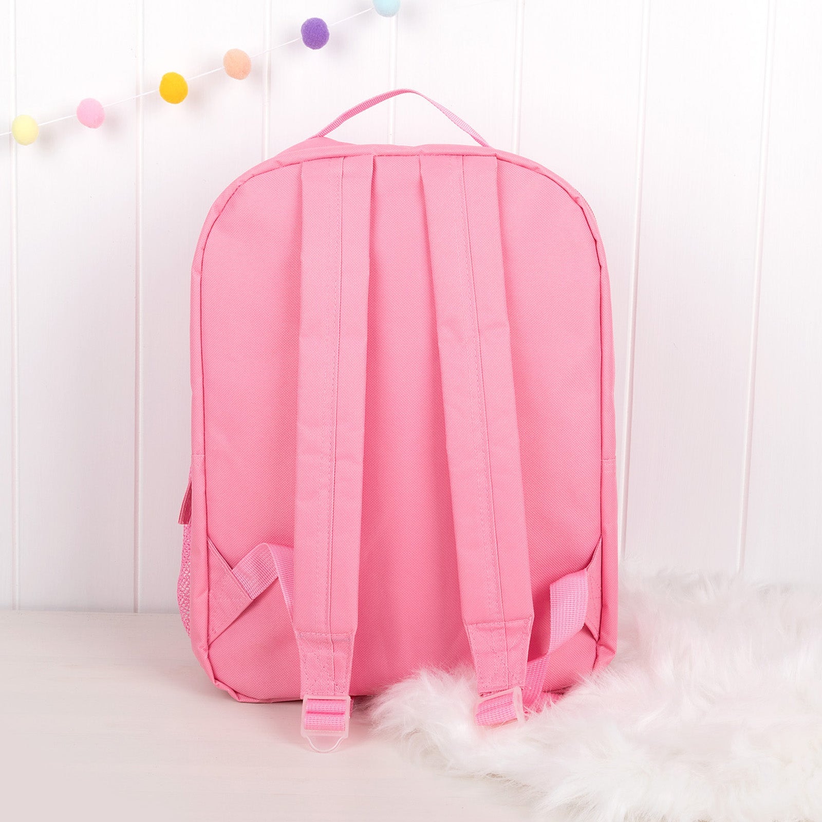 Back view of pink children’s backpack showing padded adjustable shoulder straps.