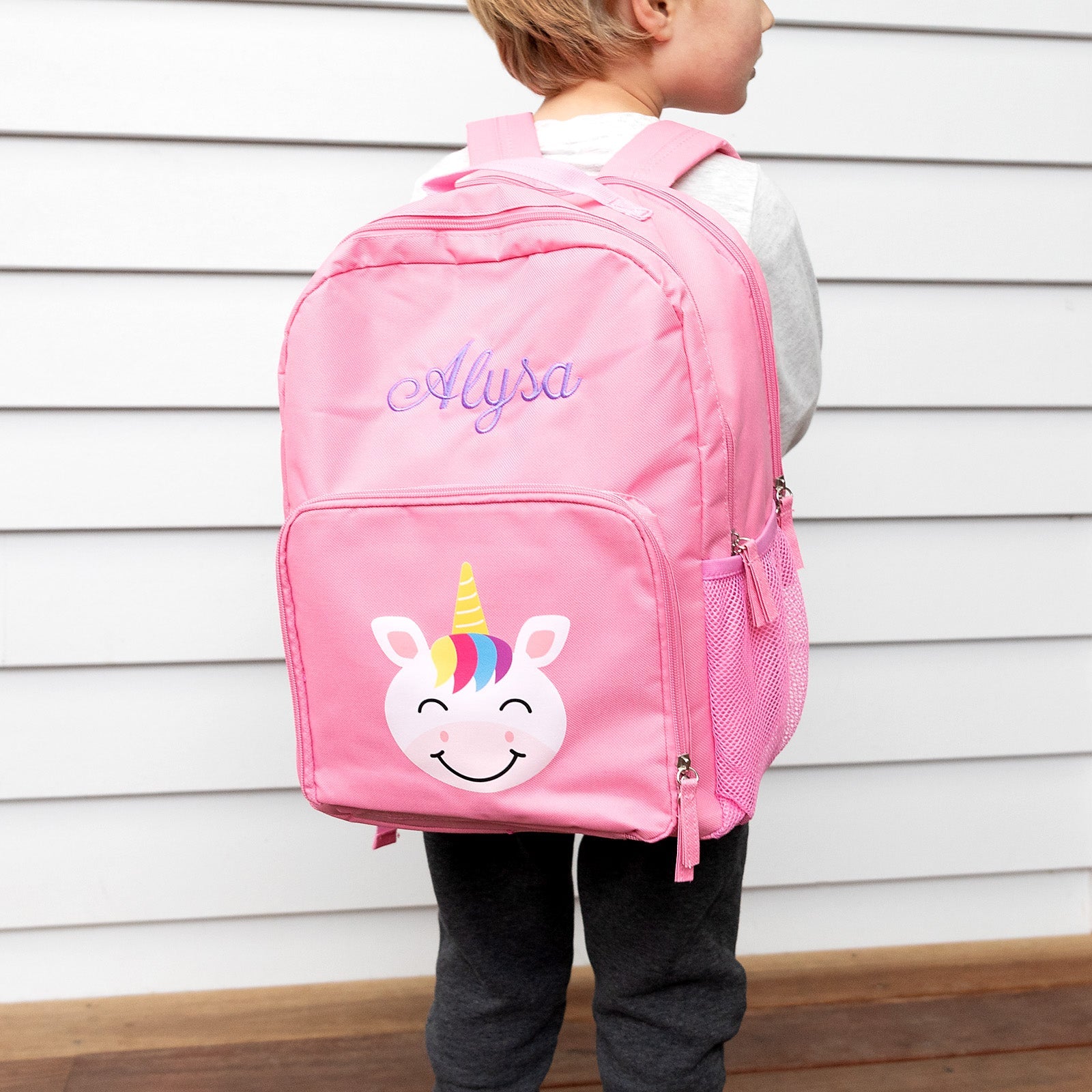 Child wearing a custom unicorn backpack, showing name embroidery and fun design.